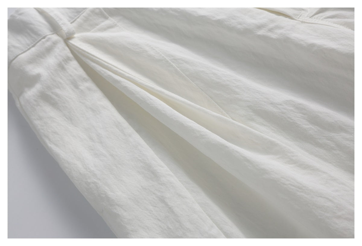 Close-up of off-white trouser fabric and a deep front pleat.