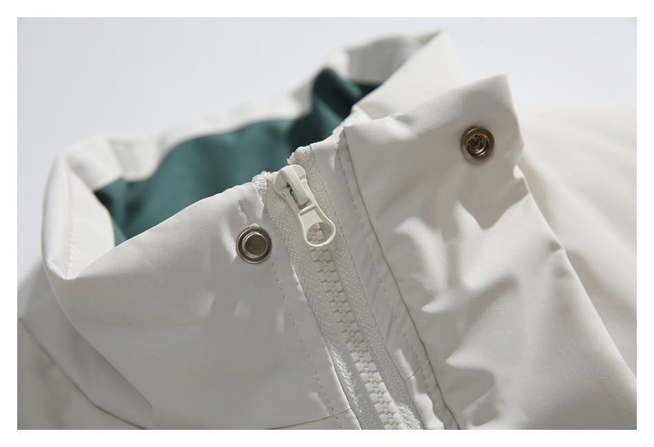 Close-up of a white jacket collar with a zipper, metal snaps, and dark teal lining.