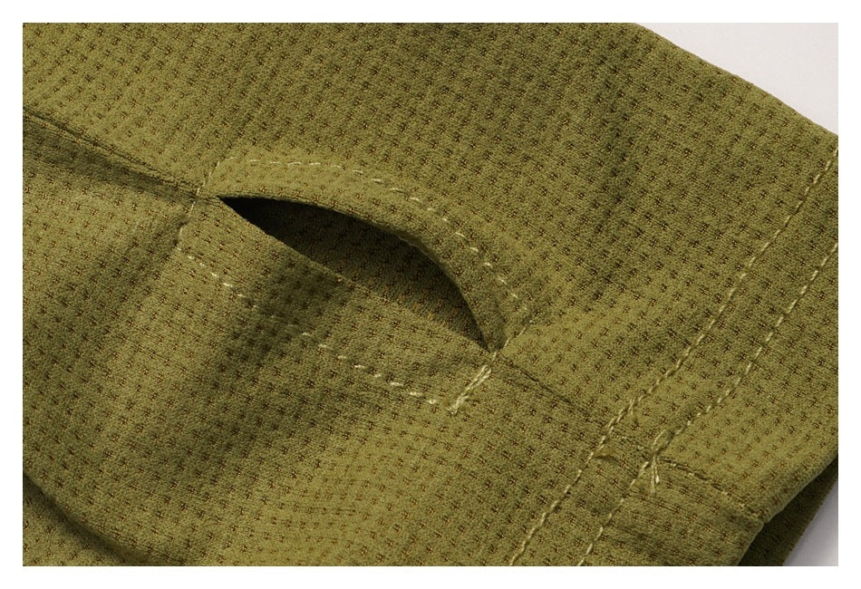 Close-up of an olive-green garment showing a small stitched slit opening and adjacent seams.