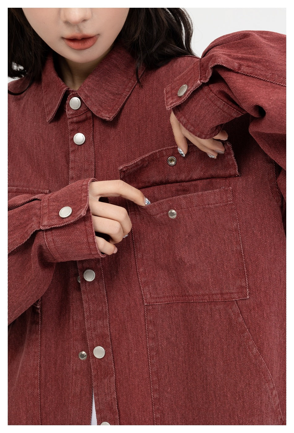 Close-up of a model showing the flap and patch chest pockets on a burgundy snap-front shirt jacket.