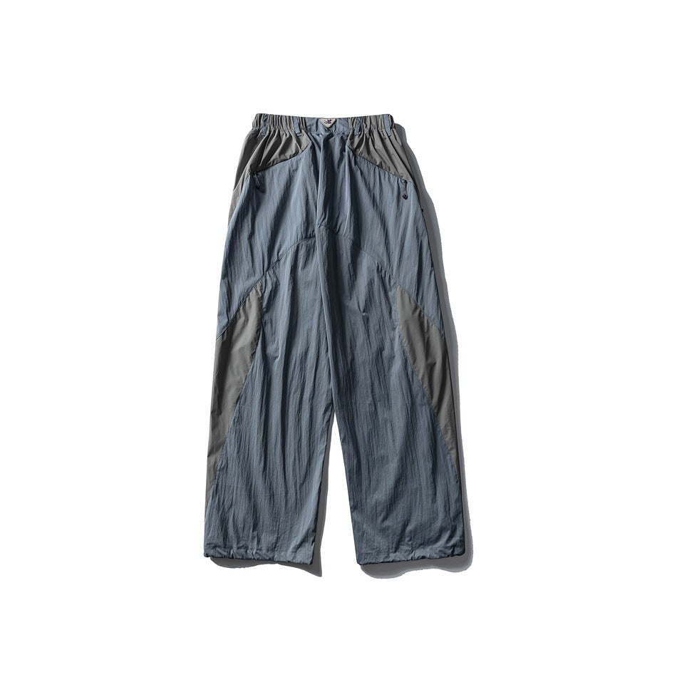 Front view of blue-gray wide-leg pants with an elastic waistband, angled pockets, and contrasting gray panels.