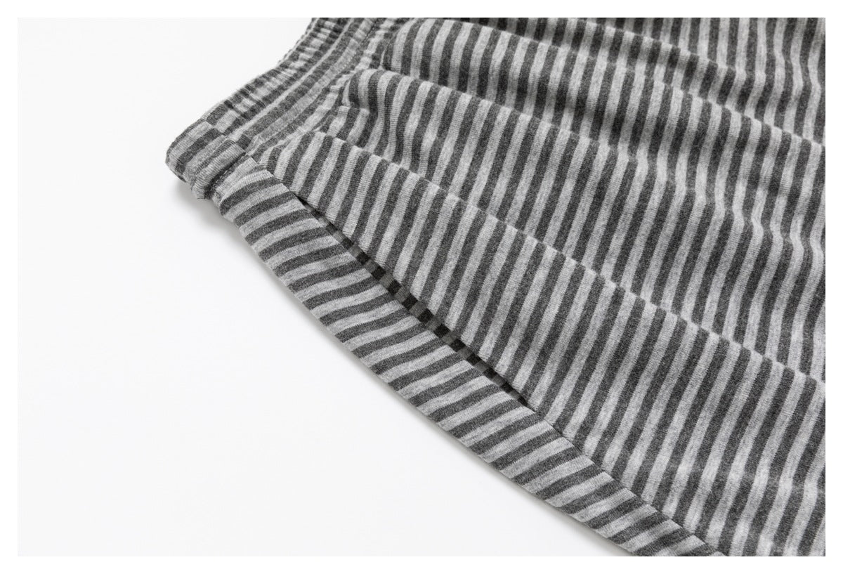 Close-up of a gray-and-charcoal striped garment showing a stitched pocket opening and waistband edge.