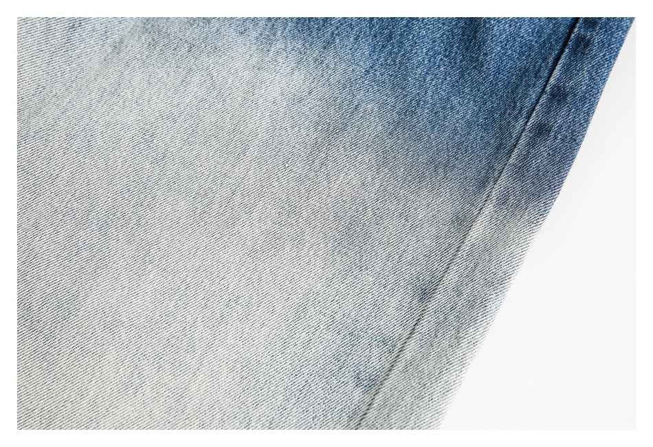 Close-up of pale blue washed denim showing a diagonal seam and faded texture.