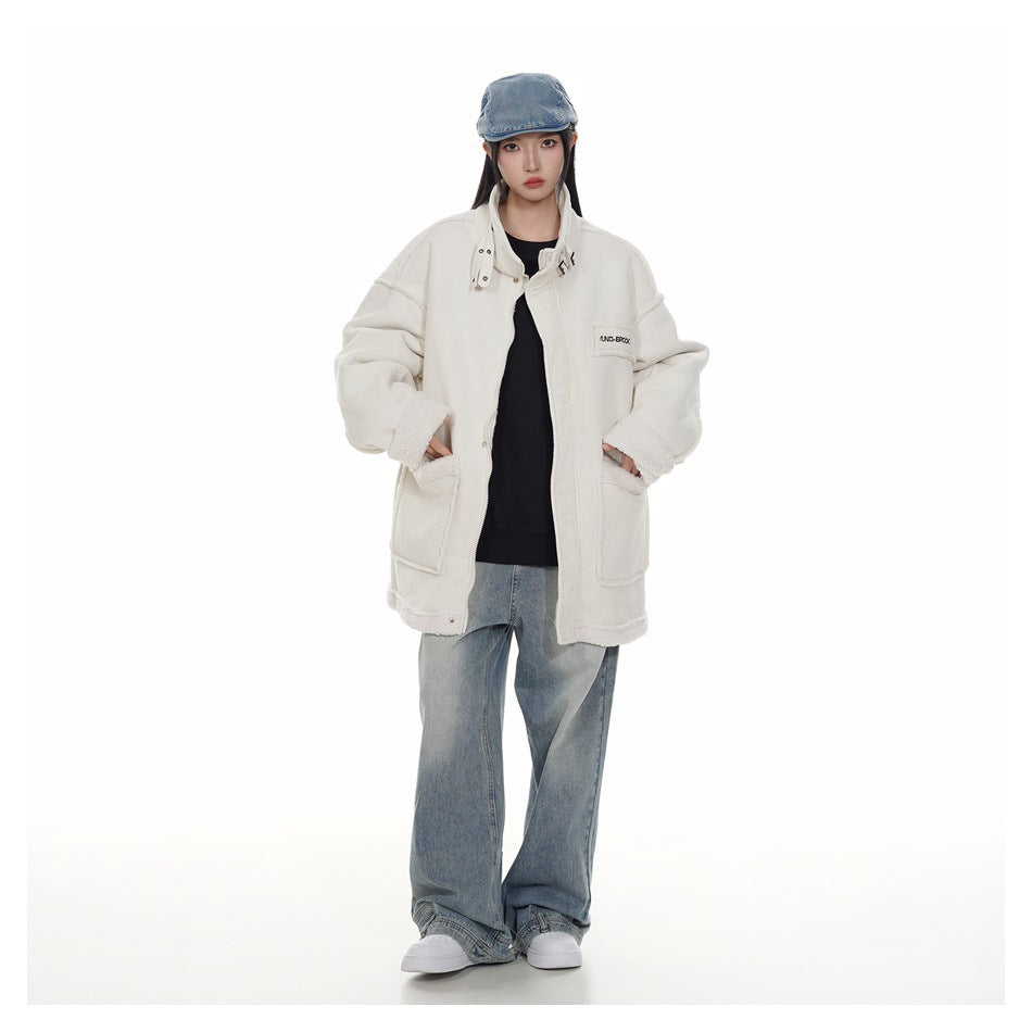 Model wearing an oversized ivory corduroy jacket with plush trim, a black top, loose jeans, and a denim cap.
