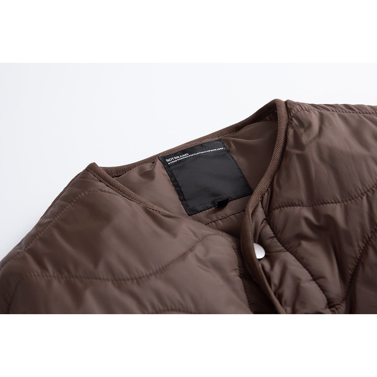 Close-up of the brown quilted jacket's neckline, binding, snap closure and black neck label.