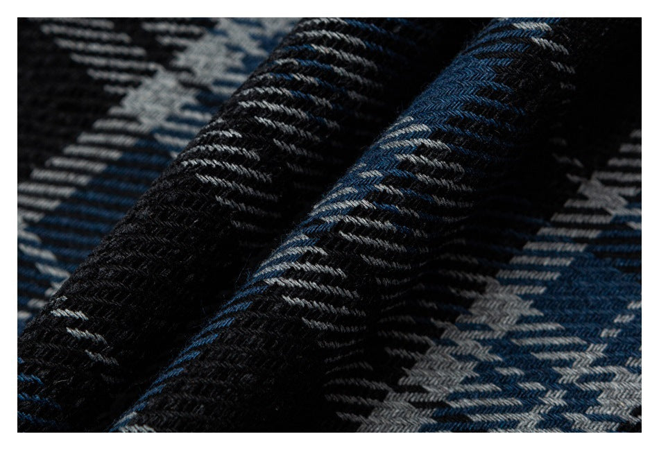 Macro view of the raised weave and folds in blue, black, and gray plaid fabric.