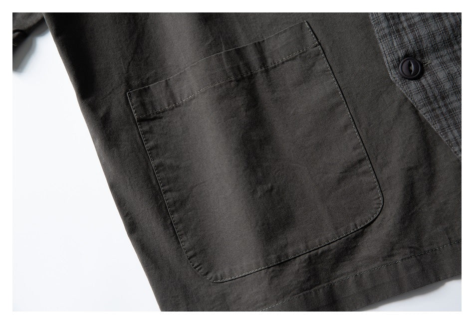Dark charcoal garment patch pocket beside a gray plaid panel and dark button.
