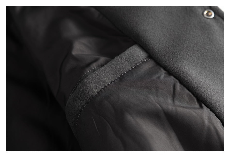 Close-up of a dark jacket showing a seam between the outer fabric and smooth lining, with a metal snap.