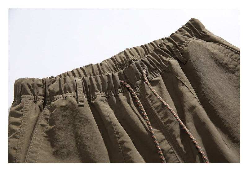 Close-up of taupe shorts showing the gathered elastic waistband, belt loops and patterned drawcord.