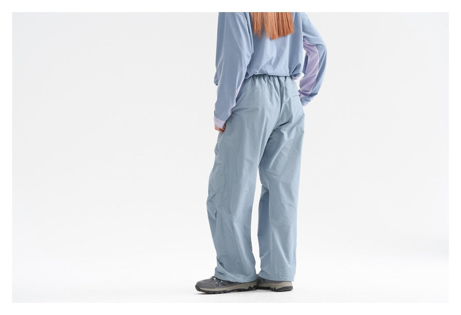 Rear view of a model wearing loose blue-gray pants with an elastic waist and a matching long-sleeve top.