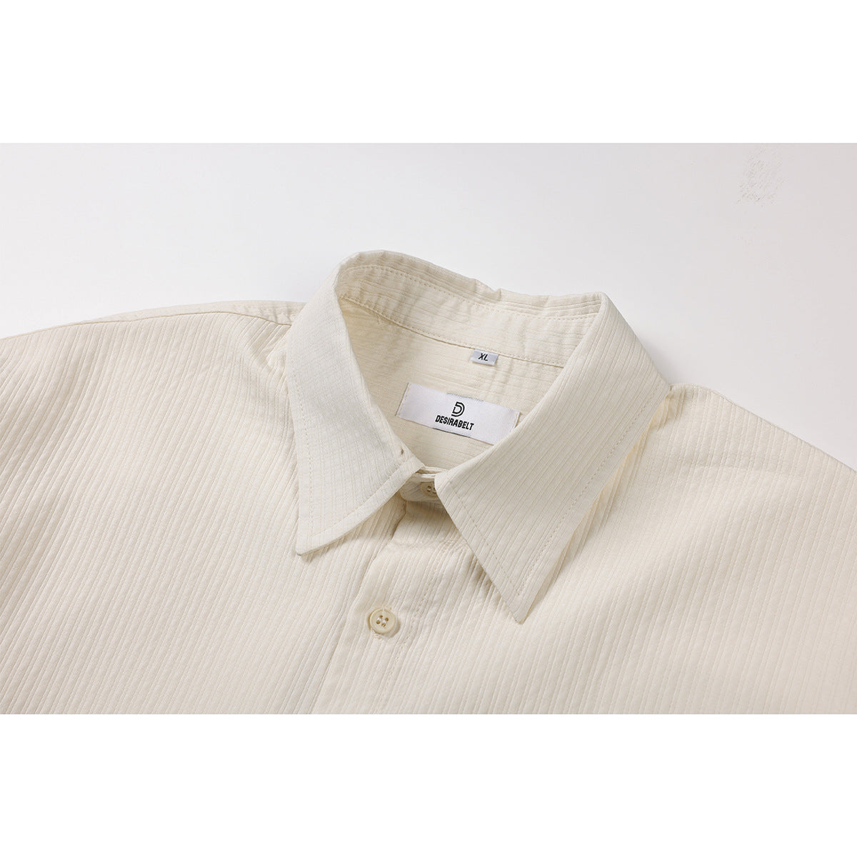 Close-up of an ivory shirt collar, neckline label, and fine vertical ribbed texture.