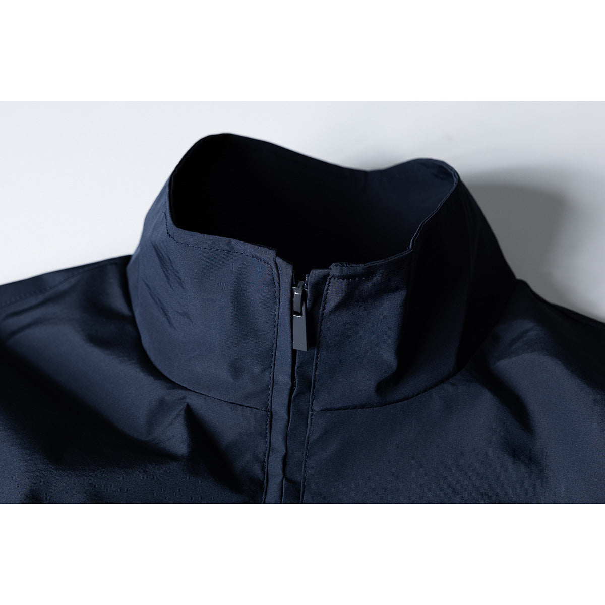 Close-up of a dark navy jacket's high stand collar and front zipper.