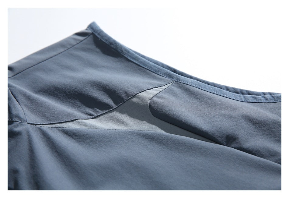 Close-up of the slate blue-gray garment's curved neckline edge and stitched upper panels.