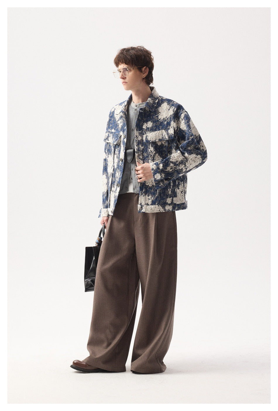 Side view of a model wearing a blue and cream floral button jacket and wide brown trousers.