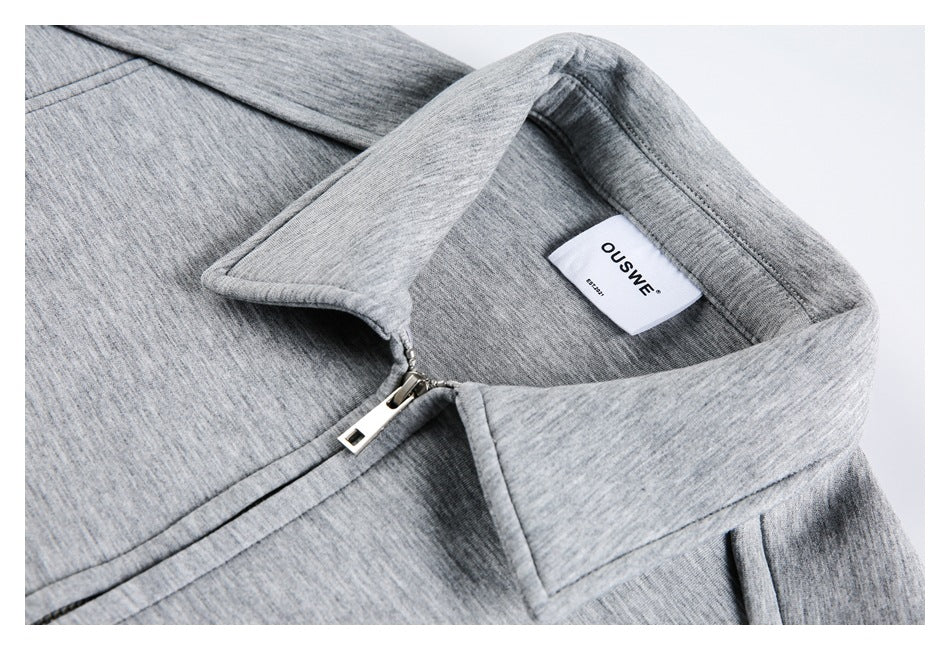 Close-up of the light gray jacket's collar, zipper, and sewn-in neck label.