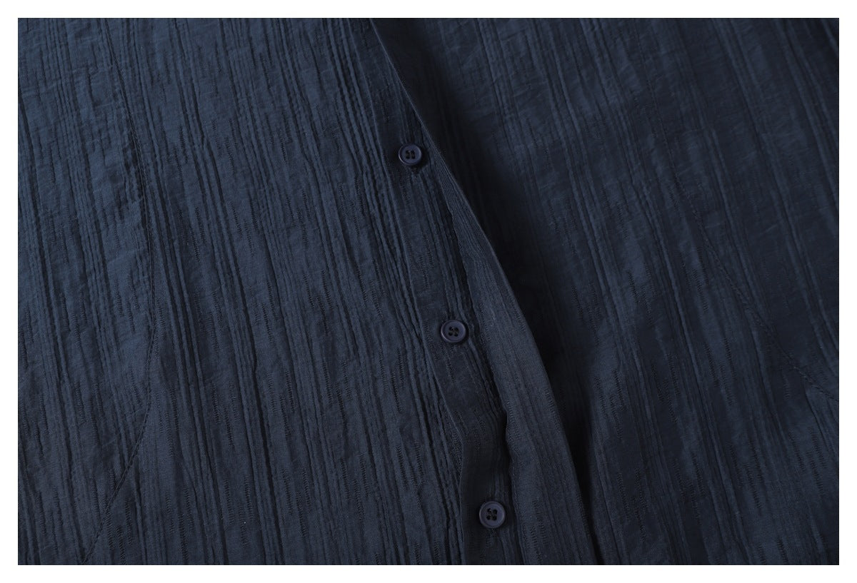 Close-up of three dark buttons on the placket of a dark navy shirt with raised vertical texture.