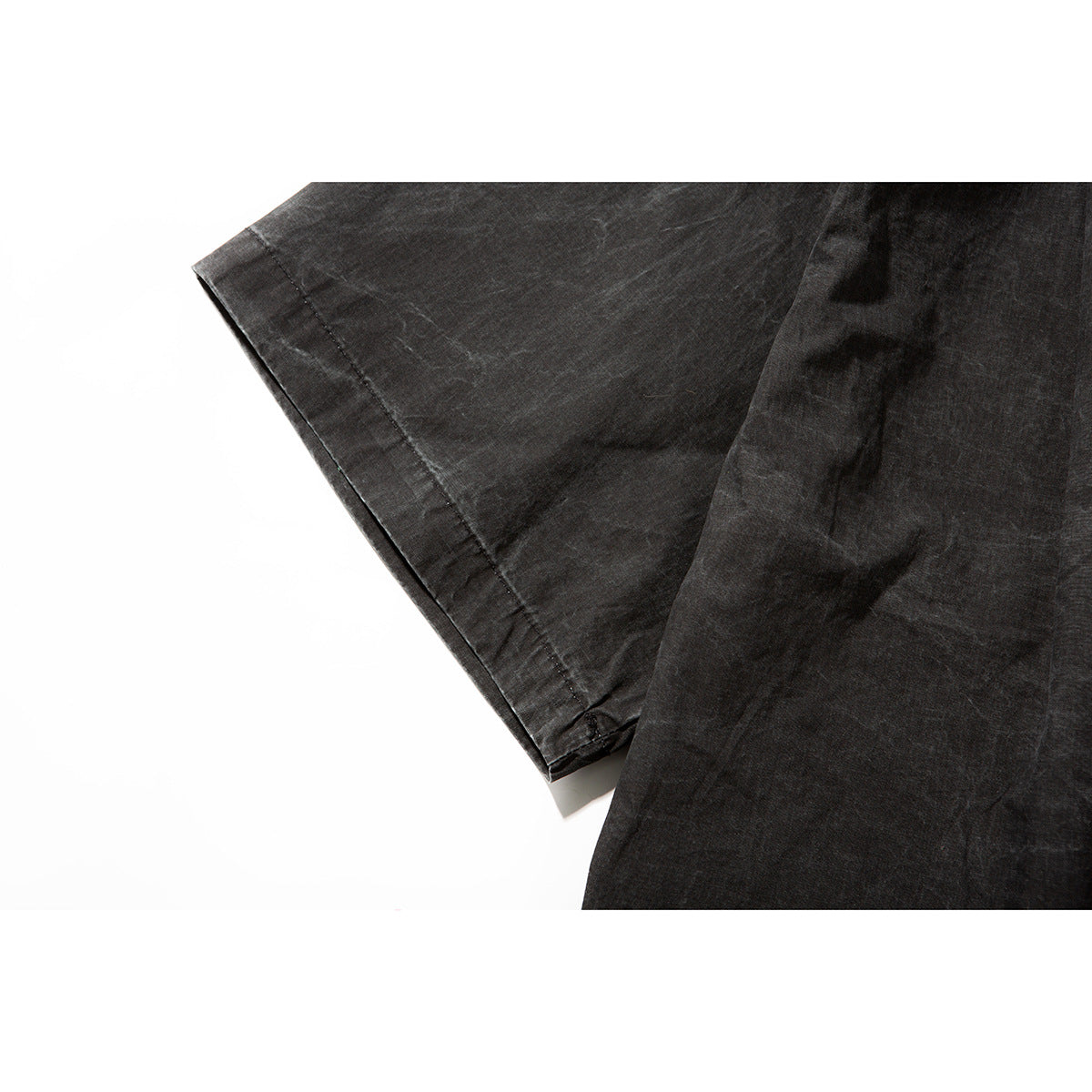 Close-up of the charcoal shirt’s short sleeve and stitched hem against a white background.