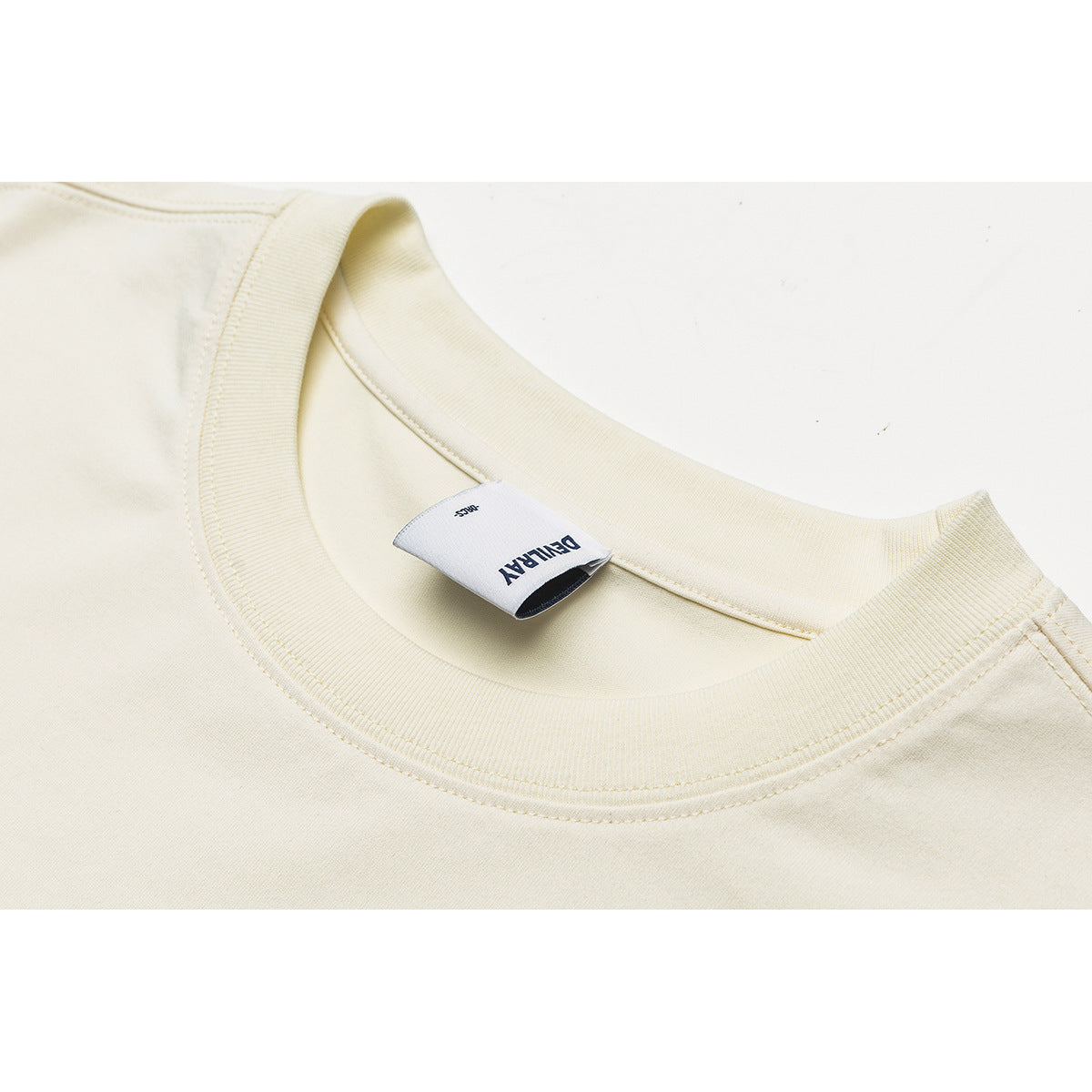 Close-up of an ivory crewneck sweatshirt collar and sewn-in neck label.