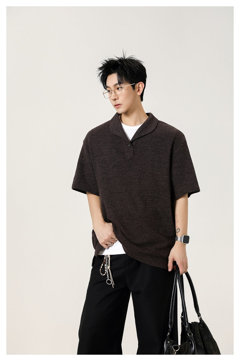 Model wearing a dark brown short-sleeve knit polo shirt over a white tee, shown from the thighs up.