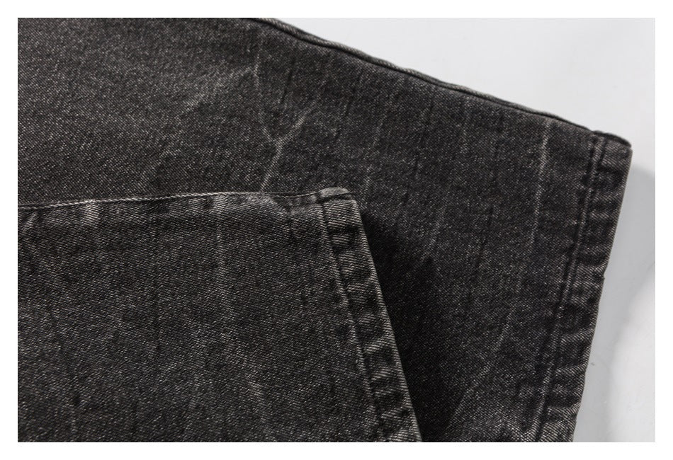 Close-up of charcoal washed denim with a folded edge and visible seam stitching.