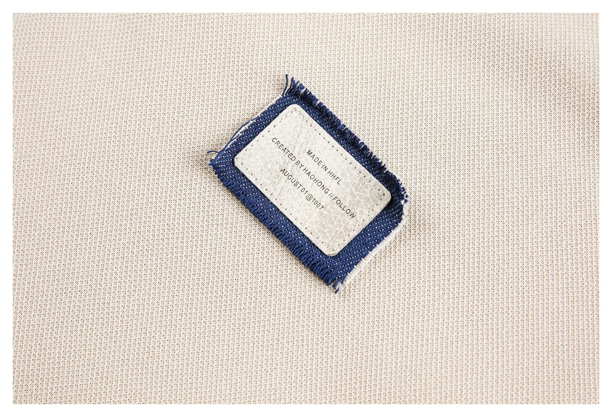 Close-up of a cream knit garment showing a small sewn label with a navy fabric border and English text.