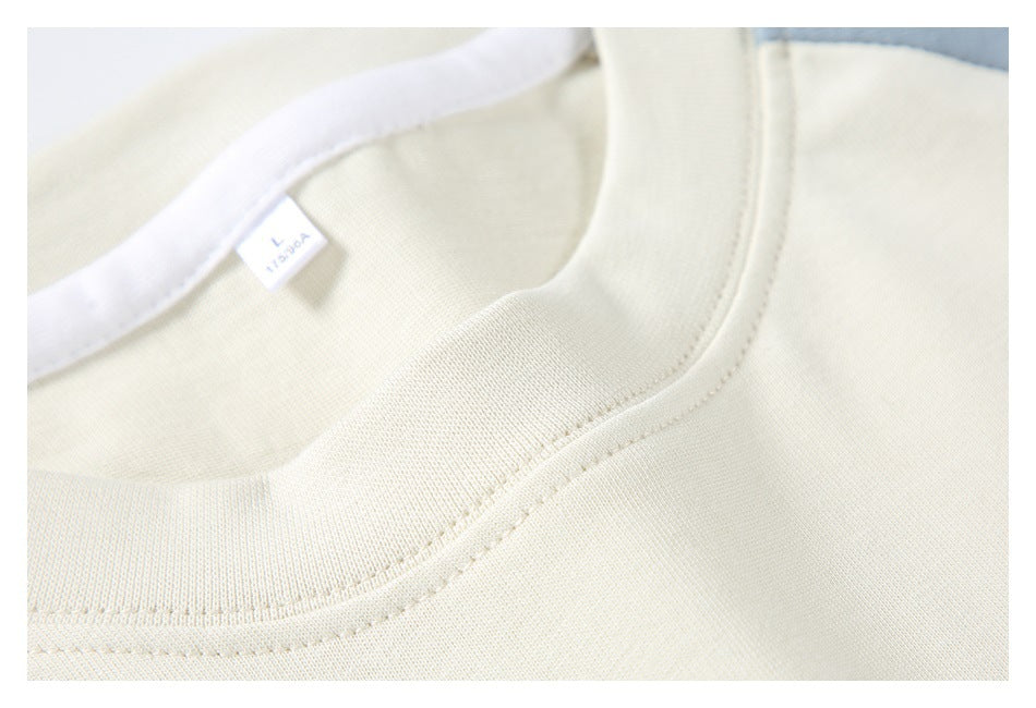 Close-up of the ivory T-shirt crew neckline stitching and small interior size label.