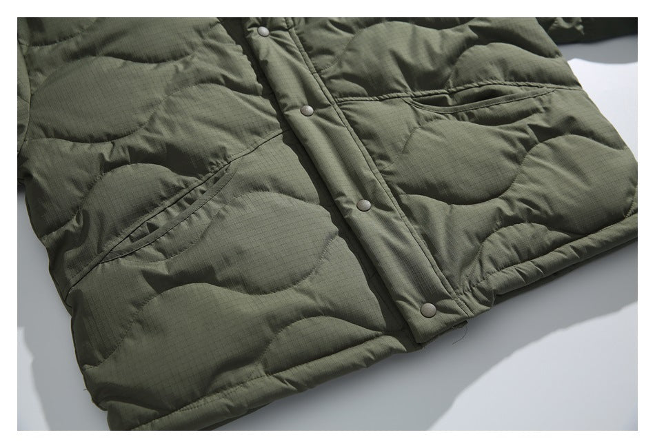 Close-up of the olive quilted jacket's front snap placket, lower hem and angled pockets.