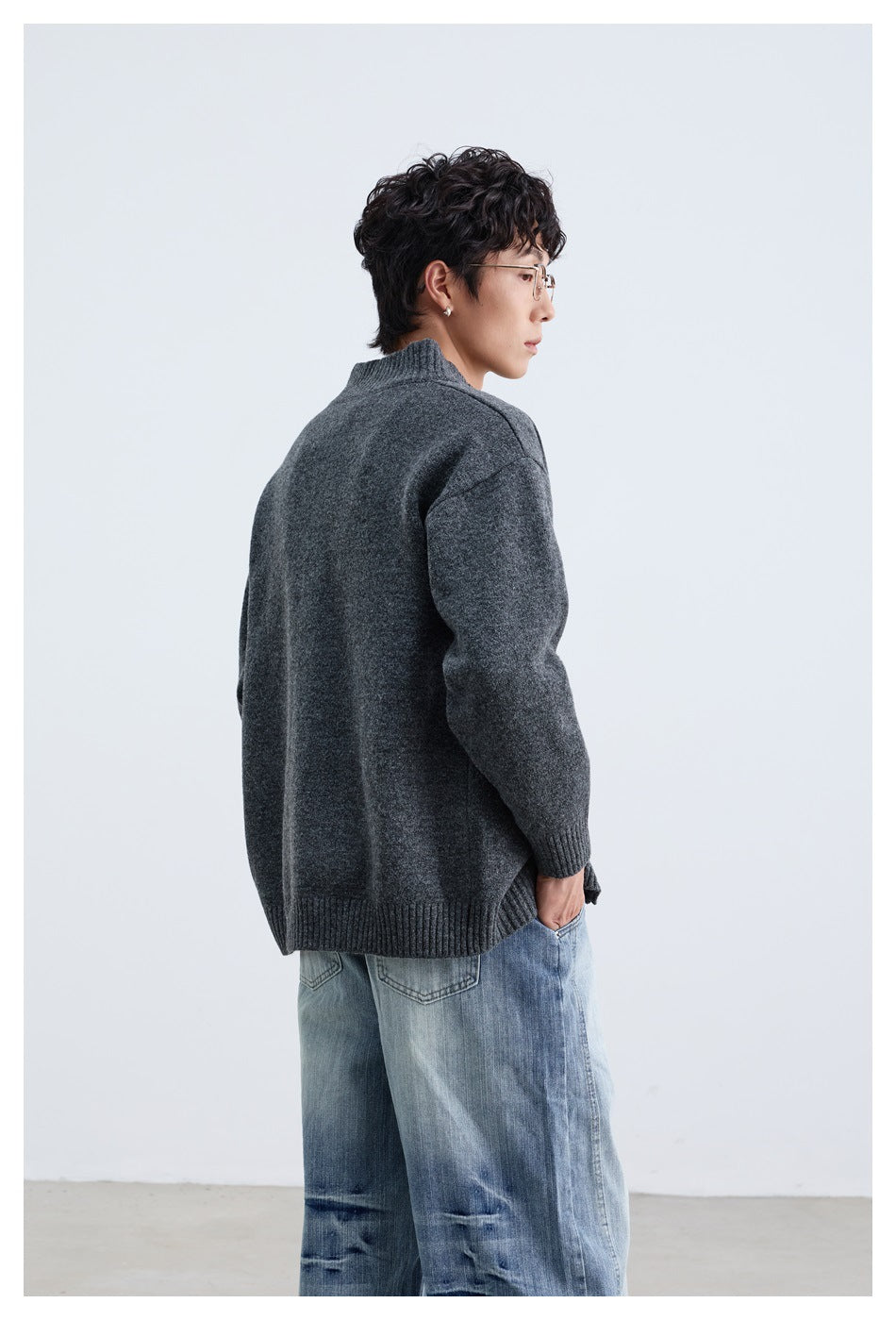 Rear three-quarter view of a model wearing a charcoal gray cardigan with a ribbed collar, cuffs and hem.