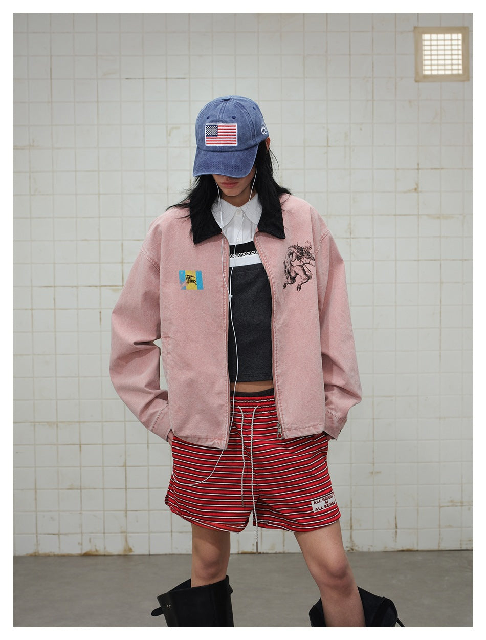 Model wearing a dusty pink zip jacket with a black collar, horse graphic and colorful chest patch.