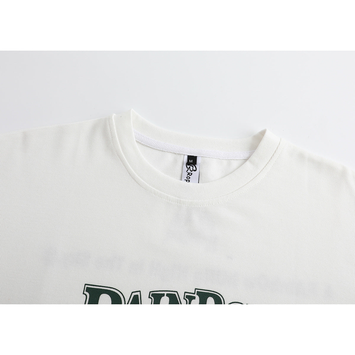 Close-up of an off-white T-shirt neckline and upper chest, with part of a dark green print visible.