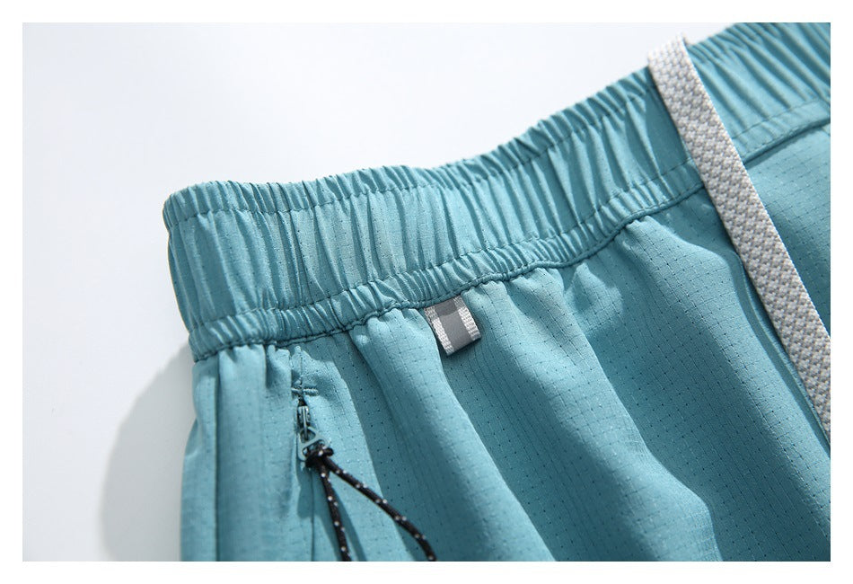 Close-up of light blue shorts with a gathered elastic waistband, black zipper pull and white drawstring.