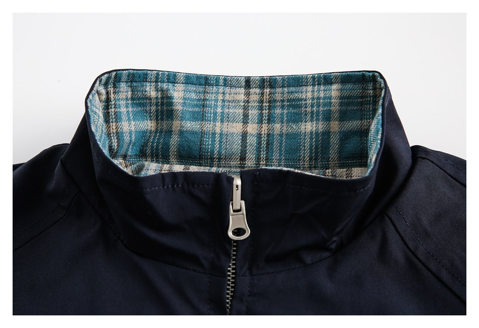 Close-up of a navy jacket's stand collar, showing teal plaid lining and a silver front zipper.