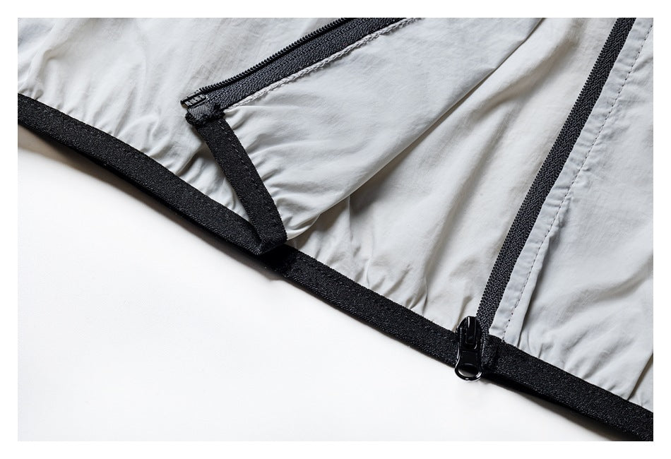Close-up of the jacket's black hem trim and zipper hardware against light gray fabric.