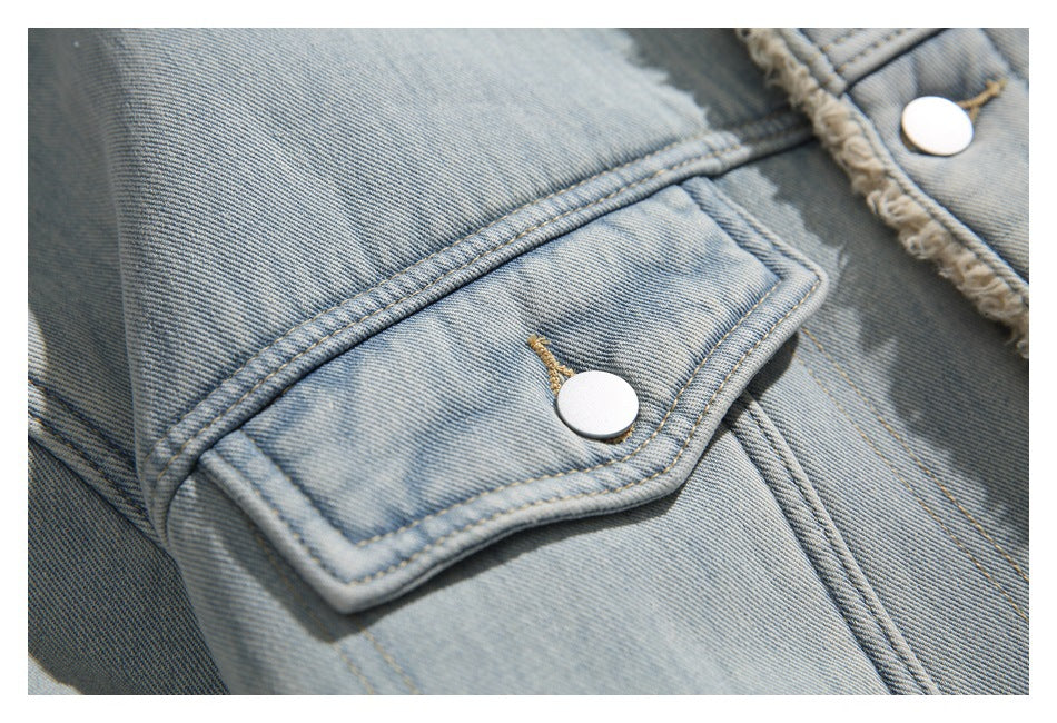 Close-up of a flap chest pocket with a metal snap on the light blue denim jacket.