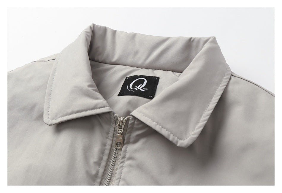 Close-up of a light gray jacket’s wide collar, sewn-in label, and front zipper.