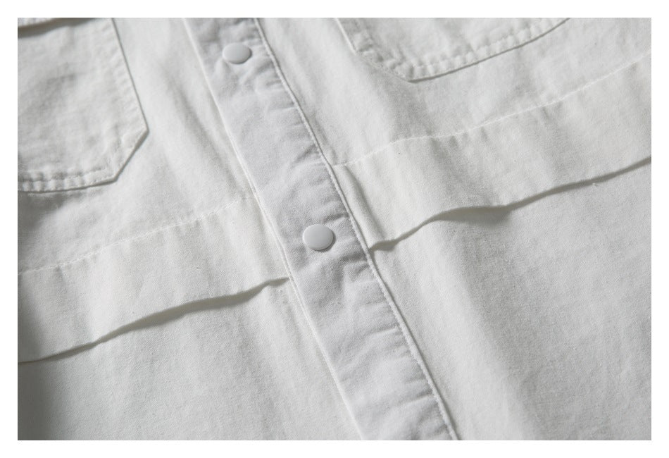 Close-up of a white shirt front with snap buttons and two chest pockets.