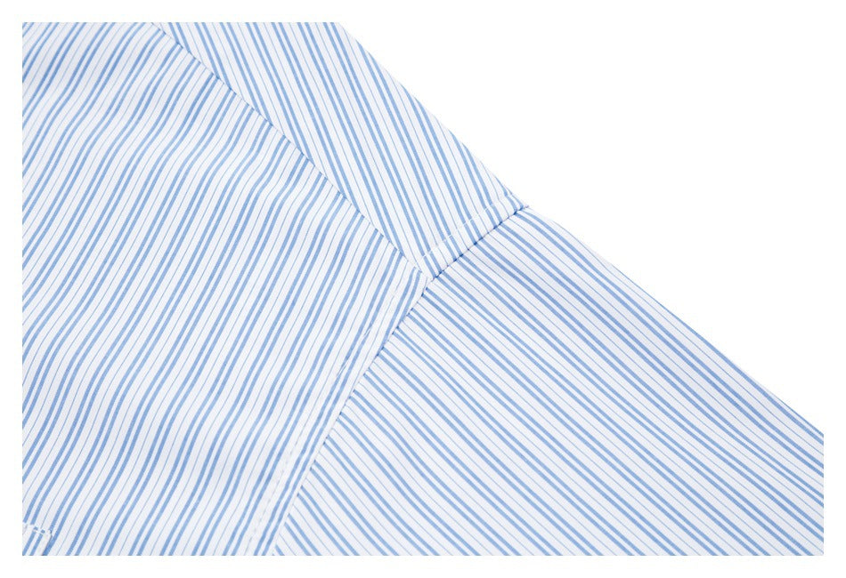 Close-up of the shoulder seam and sleeve of a white shirt with fine blue stripes.
