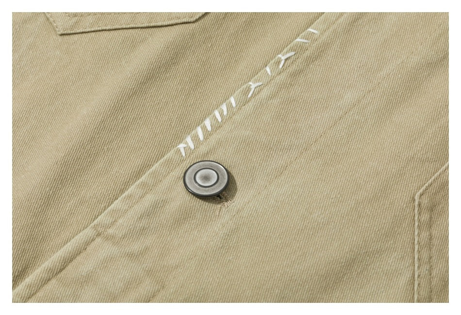 Close-up of a tan jacket with a metal button and white decorative stitching along the placket.