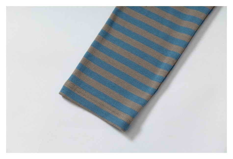 Close-up of a blue and taupe striped garment sleeve ending in a stitched hem.