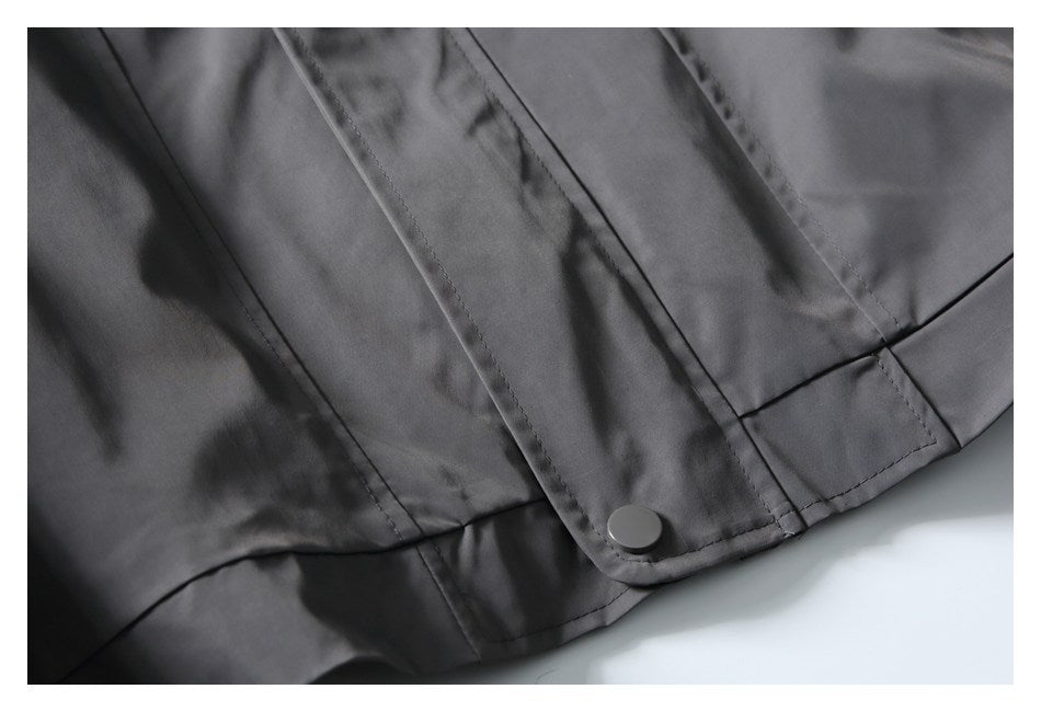 Close-up of the charcoal-gray jacket hem, showing a snap fastener and stitched front placket.