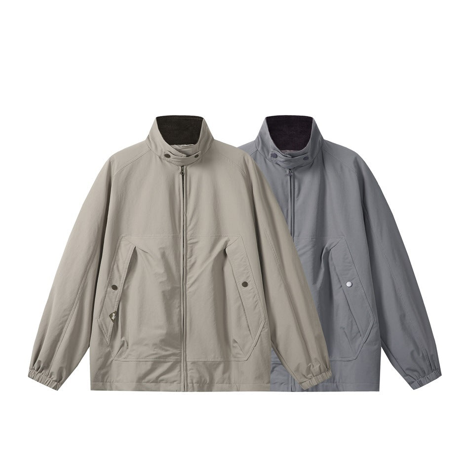 Front view of two zip-front jackets in light taupe and slate gray, with stand collars and angled snap pockets.