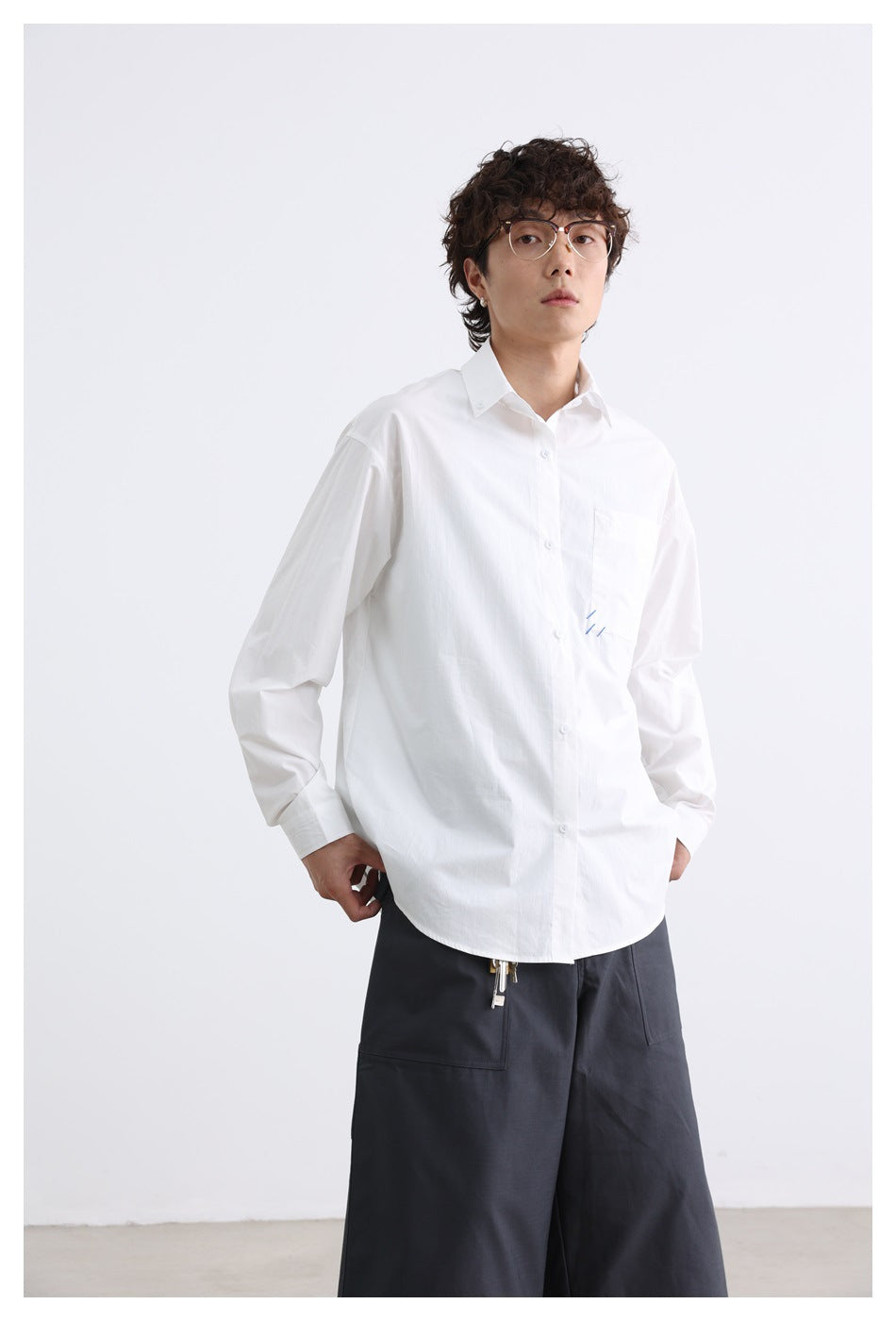 Closer front view of a model wearing a white button-down shirt with a chest pocket and charcoal shorts.