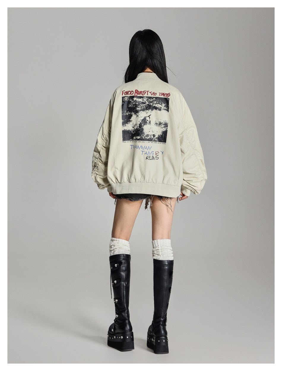 Rear view of model wearing an oversized cream bomber jacket with a large black-and-white graphic and lettering on the back.