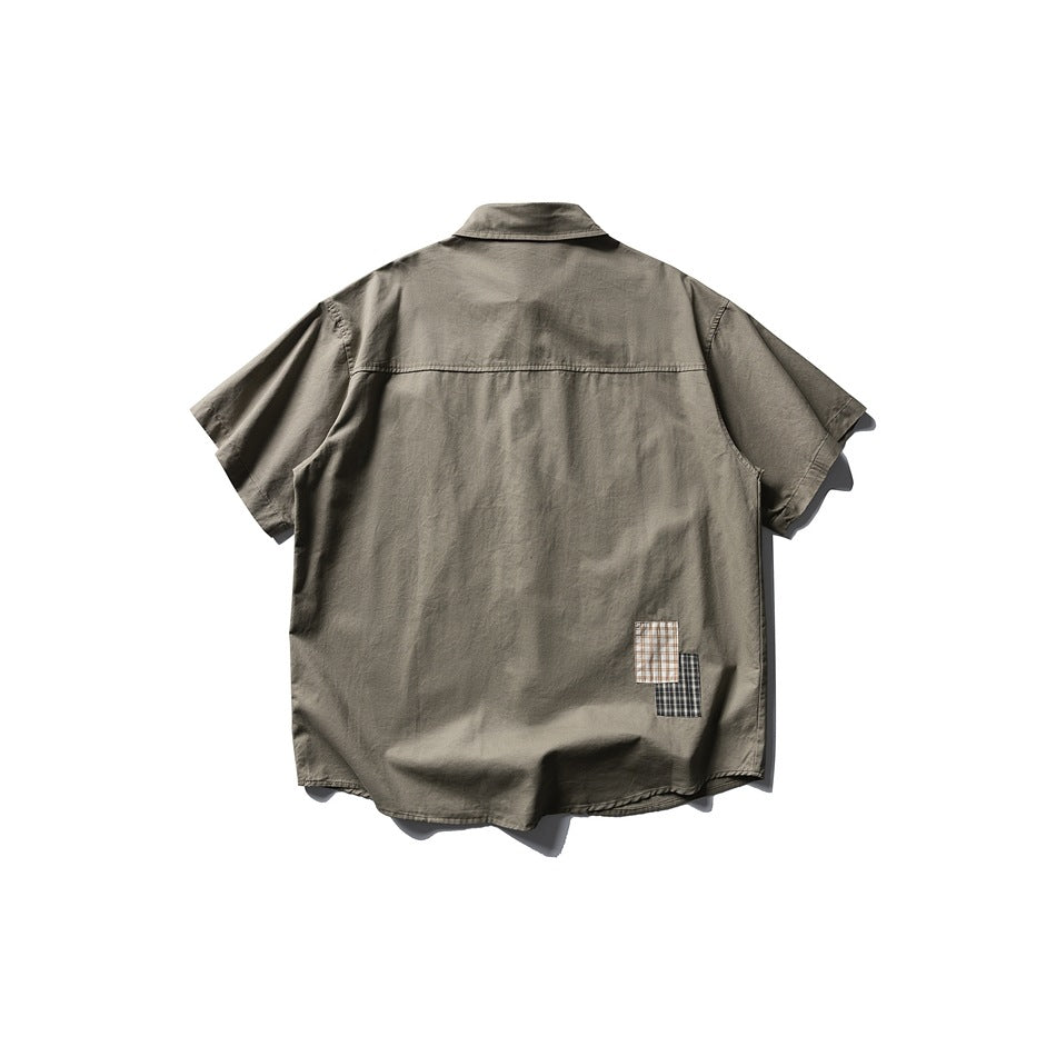 Army green short-sleeve shirt back view with back yoke seam and two small plaid patches near the hem