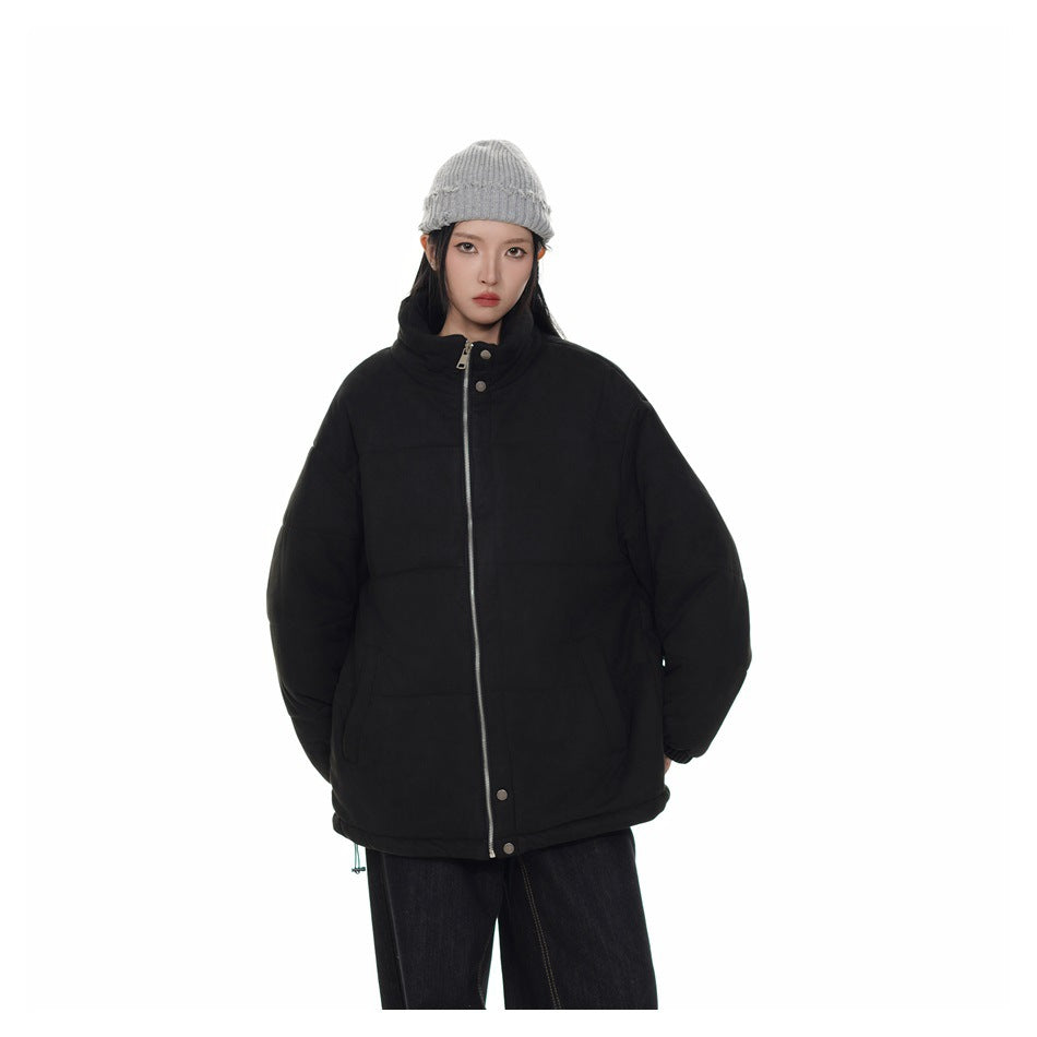 Model wearing a black quilted stand-collar jacket zipped up with a gray knit beanie and dark jeans