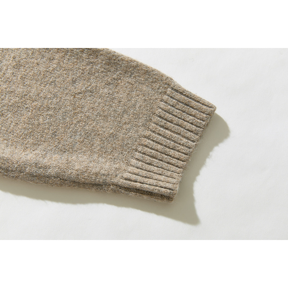 Close-up of the beige heathered sweater's long sleeve and ribbed cuff.