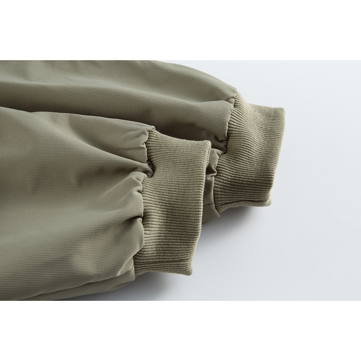 Close-up of an olive-gray jacket sleeve with a wide ribbed cuff.