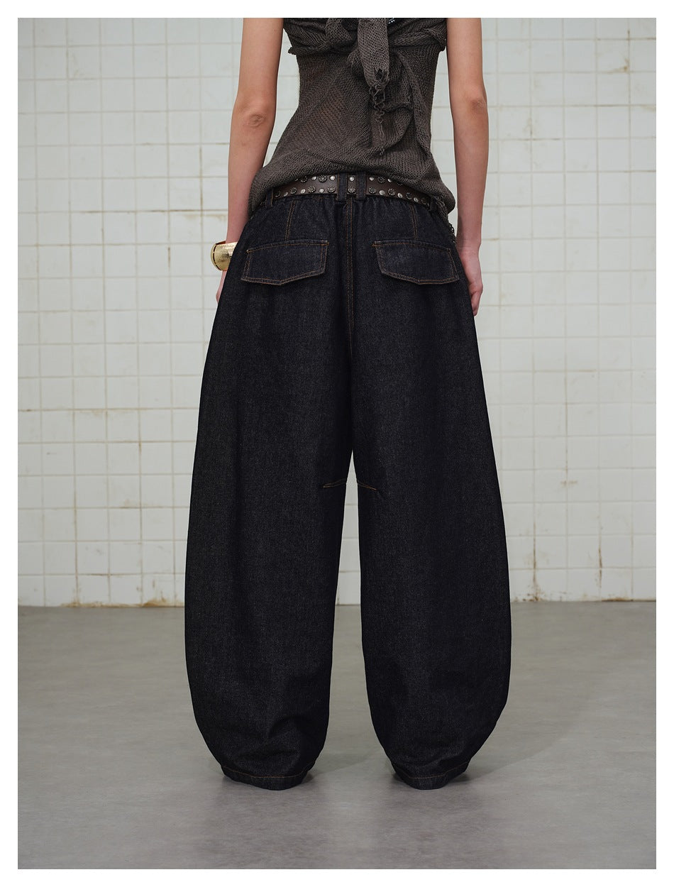 Cropped rear view of a model wearing very wide dark indigo jeans with two back pockets.