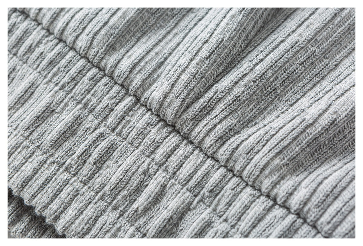 Close-up of rib-knit fabric and a stitched seam on the light gray sweater.