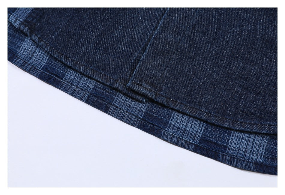 Close-up of the curved hem and stitching on dark navy fabric with a blue plaid trim.